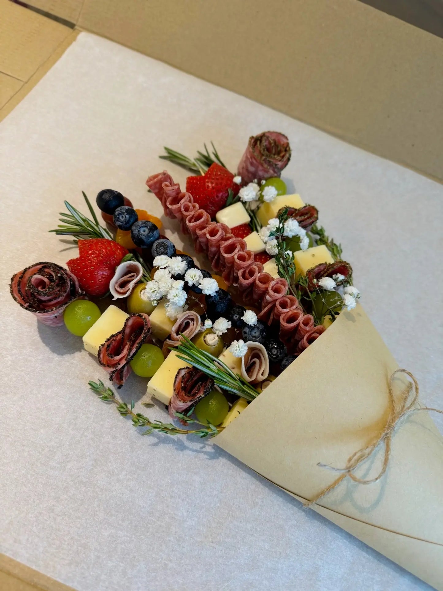 Gourmet platter with meats, cheeses, and fruits on a white surface for Valentines Day