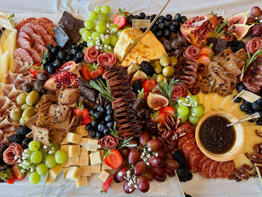 Assorted charcuterie board with meats, cheeses, fruits, and crackers on a white surface.