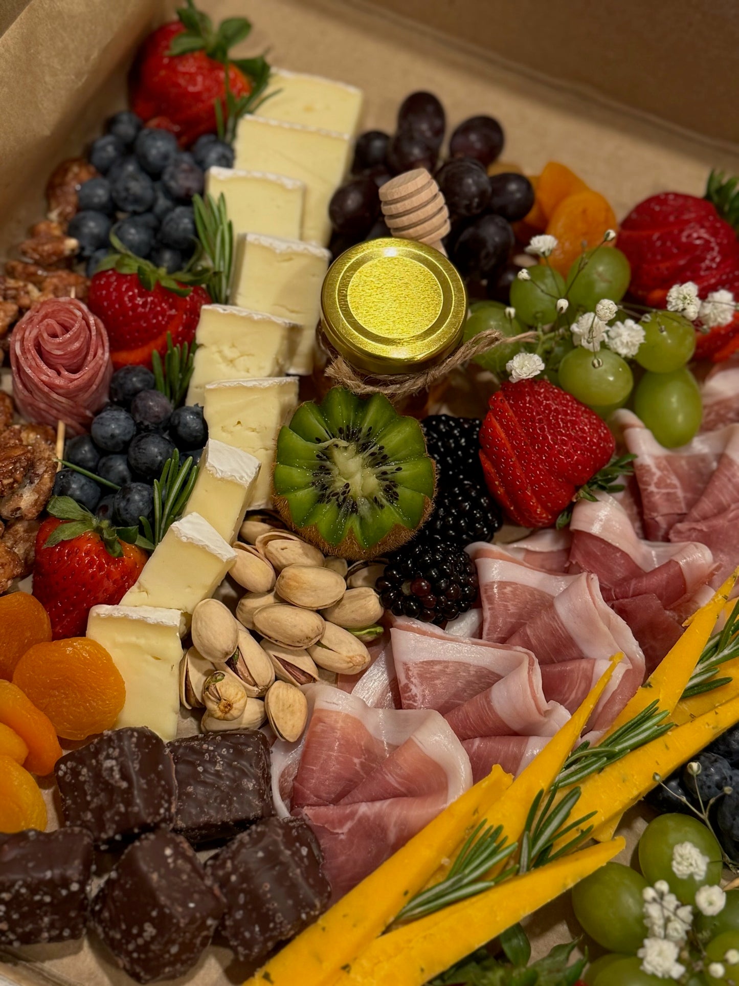Assorted charcuterie board with meats, cheeses, fruits, and nuts in a cake box