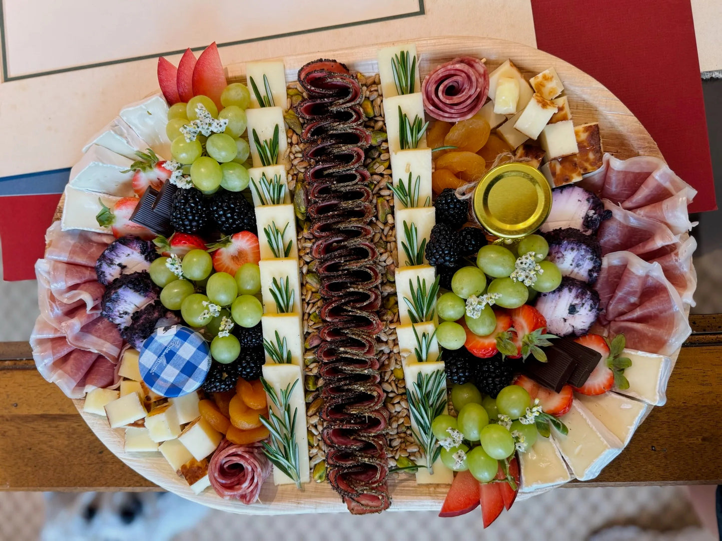 Assorted charcuterie board with meats, cheeses, fruits, and vegetables on a wooden board.