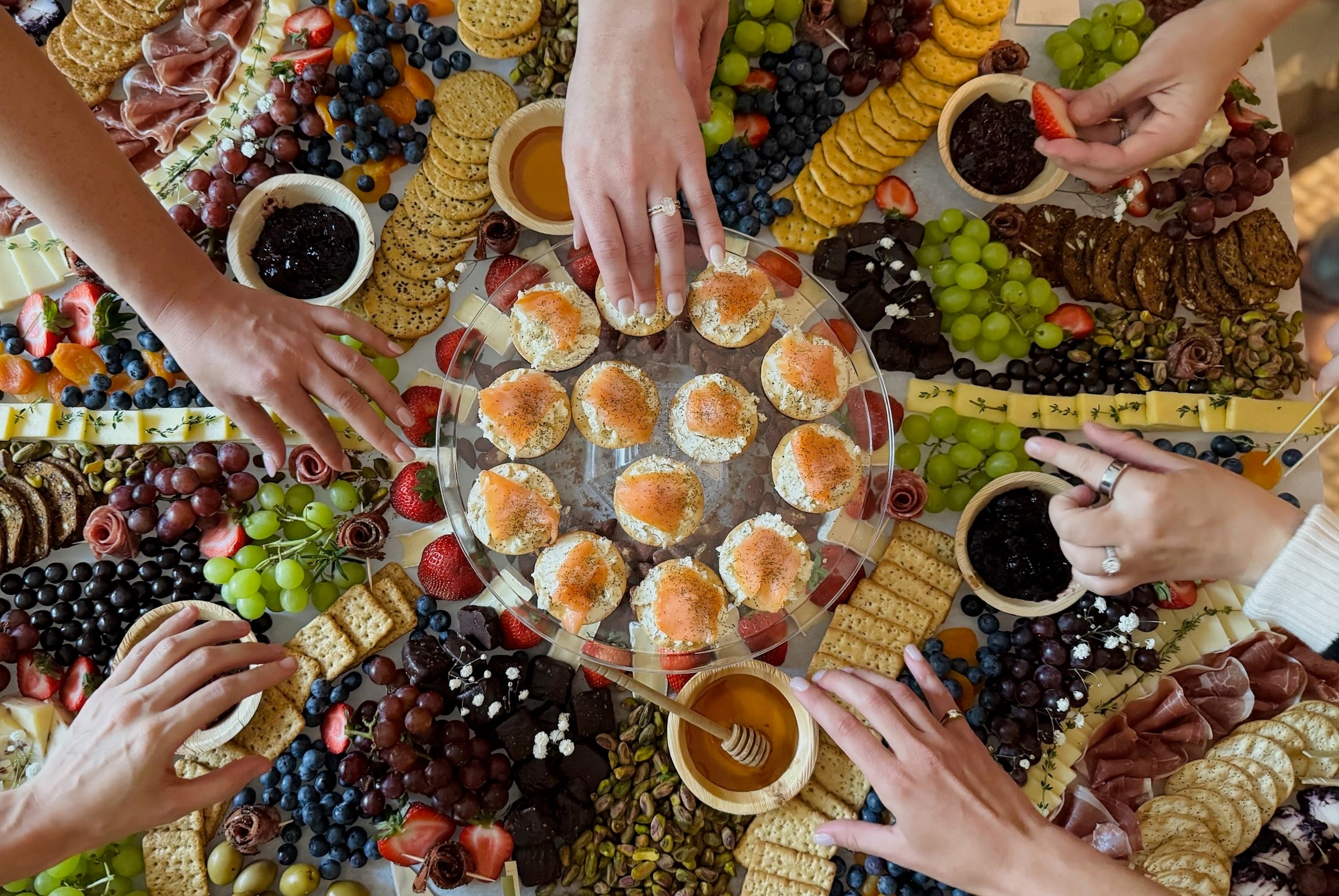 Platter of assorted finger foods with people reaching for them at a Bridal shower