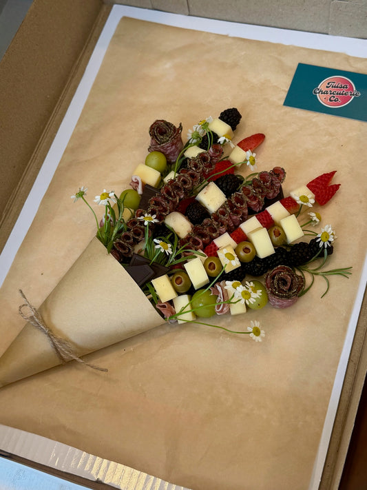 Gourmet cheese and fruit platter on a decorative paper with a visible brand label.