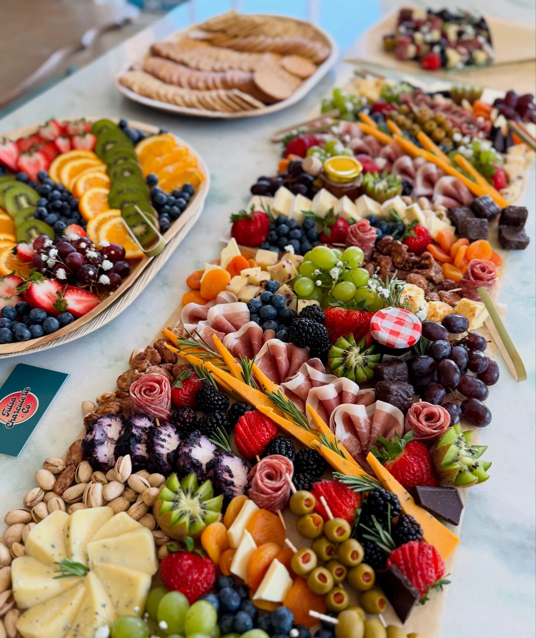 Assorted fruits, meats, and cheeses arranged on a platter with a blue background.