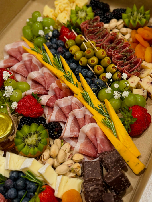 Assorted charcuterie board with meats, cheeses, fruits, and nuts in a cake box